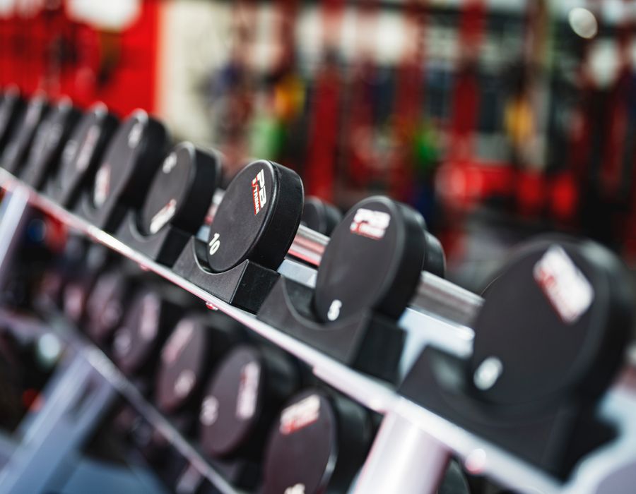 Espaço de cardio com esteiras e bikes modernas iluminado em tons quentes