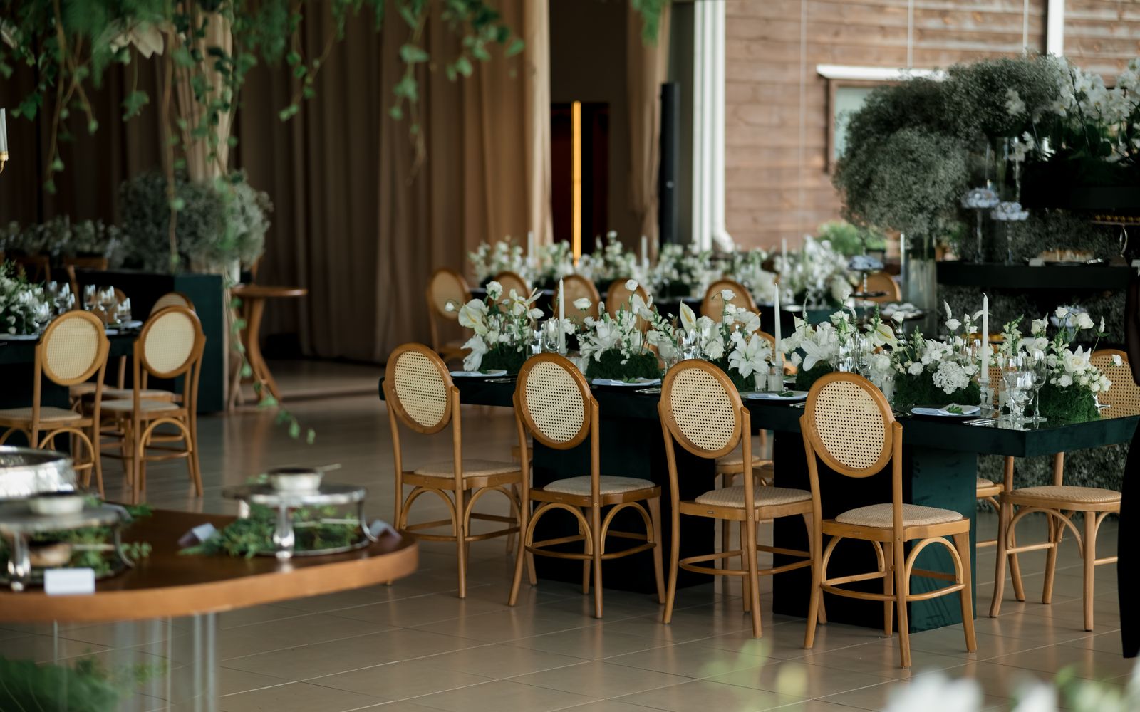 Recepção de casamento elegante decorada com mesas postas, flores e iluminação dourada na Villa Jardim