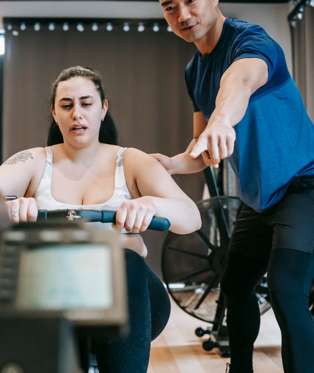 Personal trainer Lucas Ferreira orientando um aluno durante treino de musculação na academia
