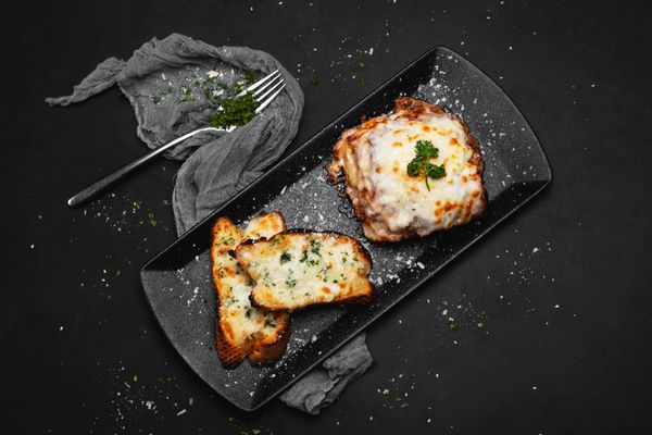 Lasanha à bolonhesa com camadas douradas de massa, ragù e béchamel